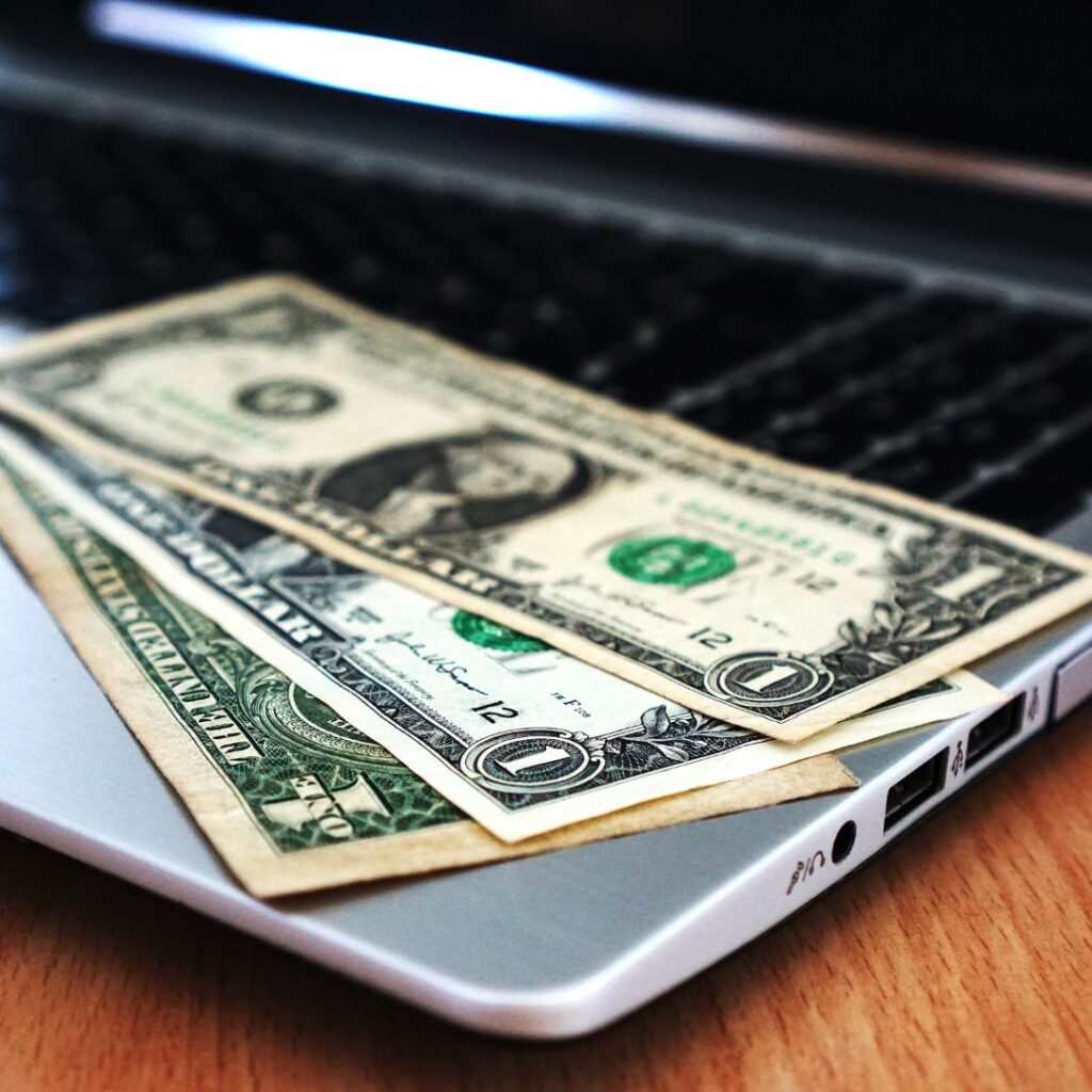 three 1 dollar bills on a laptop