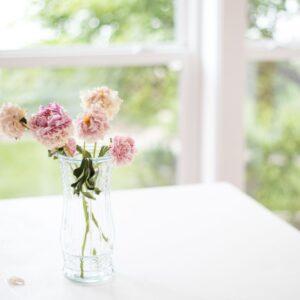 A vase of flowers on a table in a sunroom